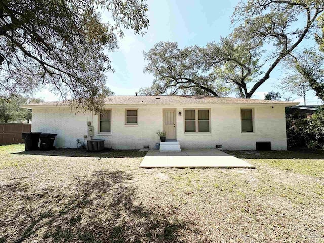 rear view of house featuring a patio area, central air condition unit, fence, brick siding, and a yard
