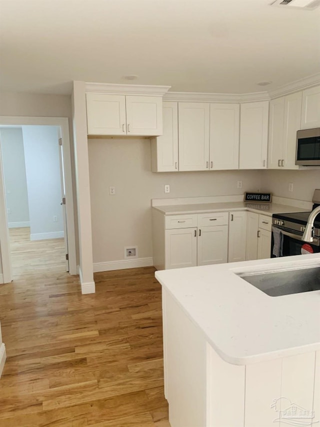 kitchen featuring sink, light wood-type flooring, white cabinetry, and stainless steel appliances