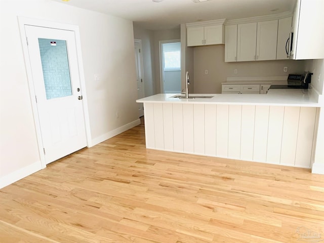 kitchen with sink, light hardwood / wood-style floors, kitchen peninsula, and stove