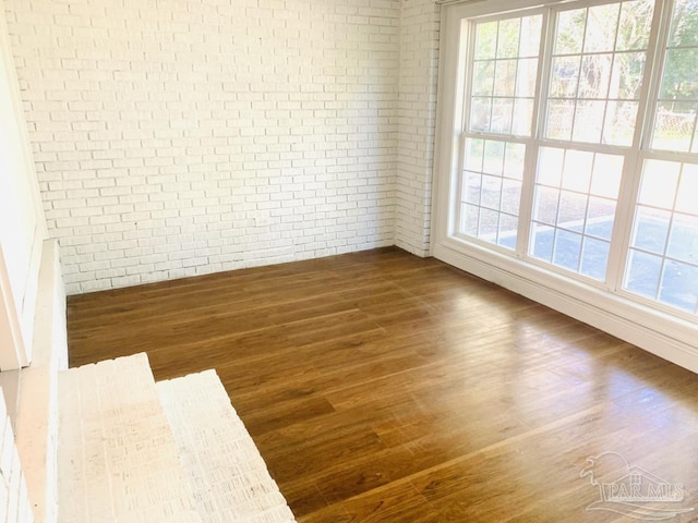 spare room with dark wood-type flooring and brick wall