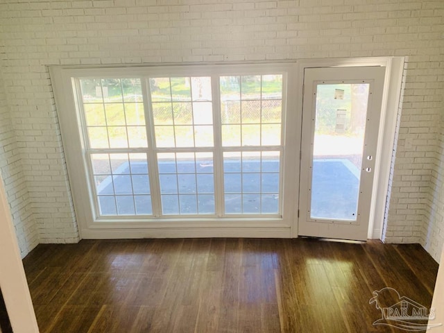 entryway featuring brick wall and dark wood-type flooring