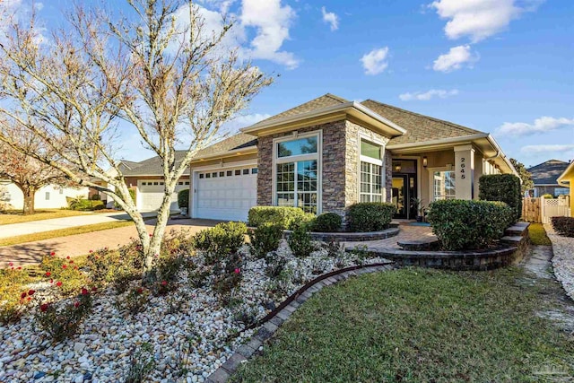 view of front facade with a garage, stone siding, concrete driveway, and fence