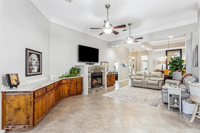 living room with crown molding, ceiling fan with notable chandelier, and a stone fireplace