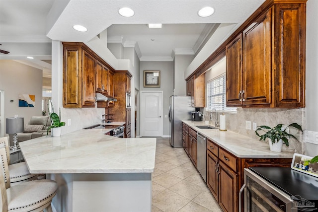 kitchen with a kitchen bar, stainless steel appliances, sink, backsplash, and kitchen peninsula