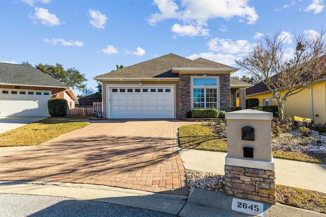 view of front of house with stone siding, decorative driveway, an attached garage, and roof with shingles