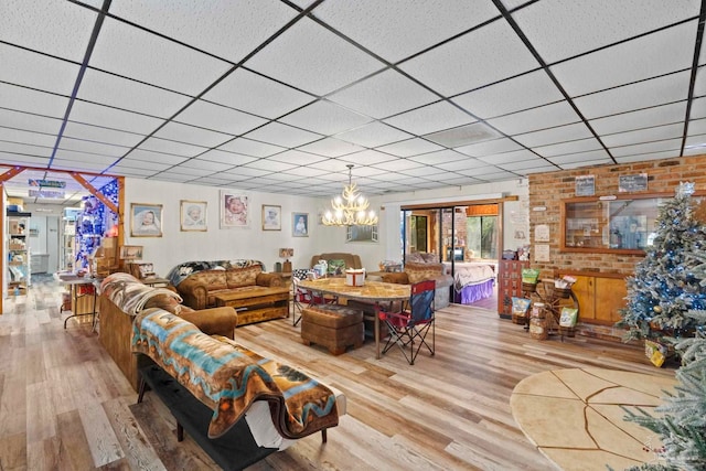 living room featuring a paneled ceiling, an inviting chandelier, and wood-type flooring