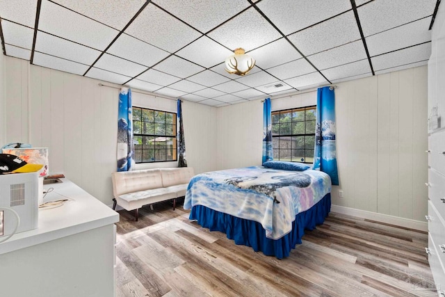 bedroom with multiple windows, a paneled ceiling, and wood-type flooring