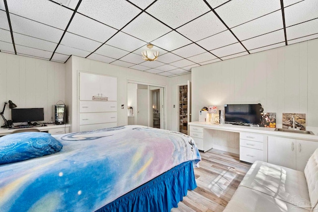 bedroom featuring sink, wood walls, and light hardwood / wood-style floors