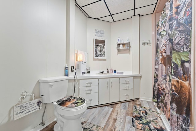 bathroom featuring vanity, hardwood / wood-style flooring, a paneled ceiling, and toilet