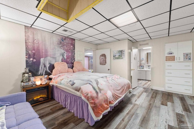 bedroom featuring a paneled ceiling, hardwood / wood-style floors, and connected bathroom