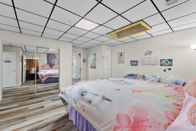 bedroom featuring a drop ceiling, hardwood / wood-style flooring, and a closet