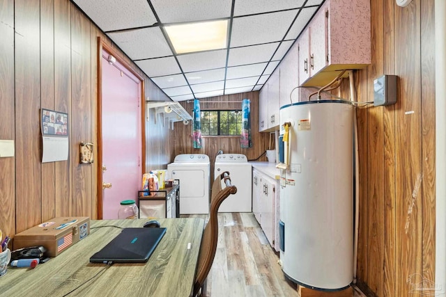 washroom featuring light wood-type flooring, water heater, cabinets, washing machine and clothes dryer, and wood walls