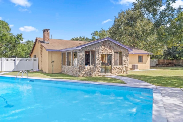 back of property featuring a fenced in pool, a lawn, and central AC