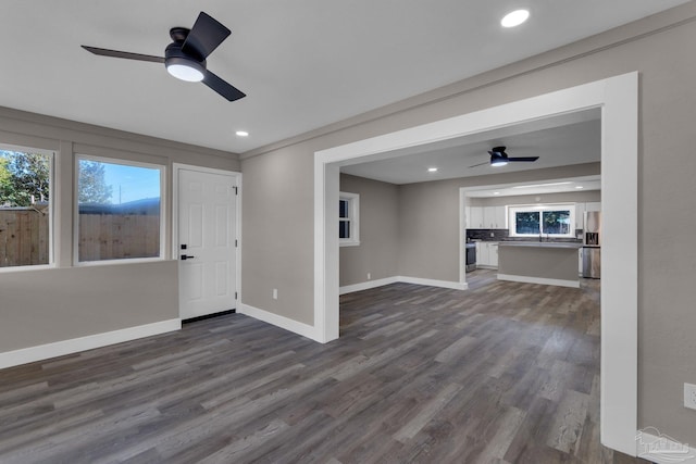 unfurnished living room featuring ceiling fan and dark wood-type flooring