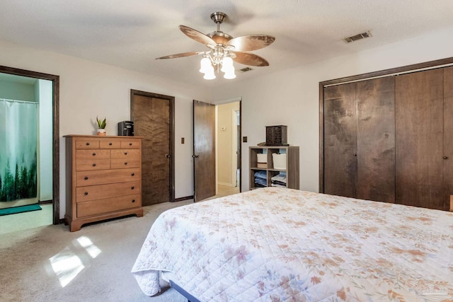 bedroom featuring light colored carpet, ceiling fan, visible vents, and two closets