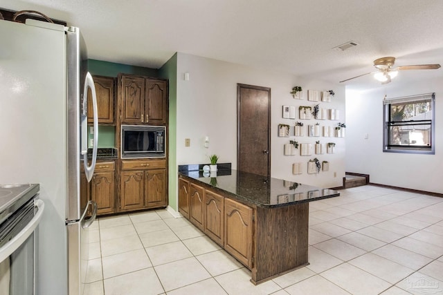 kitchen with visible vents, ceiling fan, a peninsula, stainless steel appliances, and light tile patterned flooring