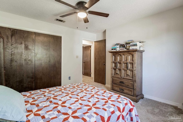 bedroom with light carpet, visible vents, a ceiling fan, a textured ceiling, and a closet