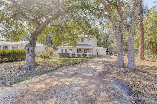 view of front of house with driveway, covered porch, a garage, and a front yard