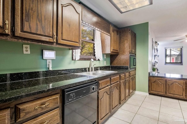 kitchen featuring light tile patterned floors, ceiling fan, a sink, dark stone counters, and black appliances