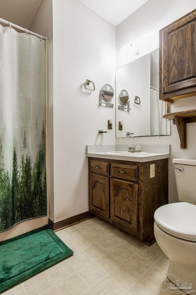 full bath with a textured ceiling, curtained shower, toilet, vanity, and baseboards