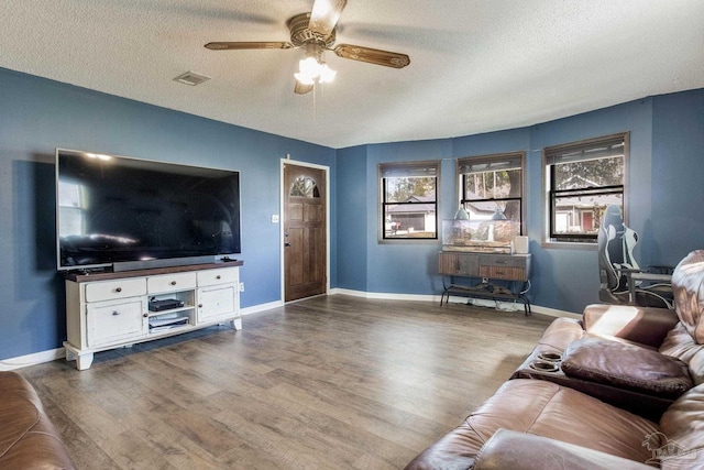 living area featuring a ceiling fan, wood finished floors, visible vents, and a textured ceiling