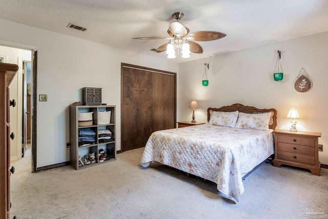 carpeted bedroom with ceiling fan, a textured ceiling, visible vents, and a closet