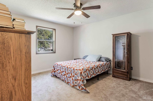 carpeted bedroom with a ceiling fan, baseboards, and a textured ceiling