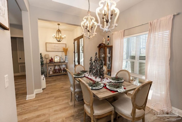 dining space featuring light wood-type flooring and a chandelier