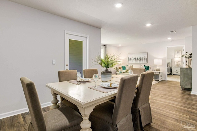 dining space with wood-type flooring and a textured ceiling