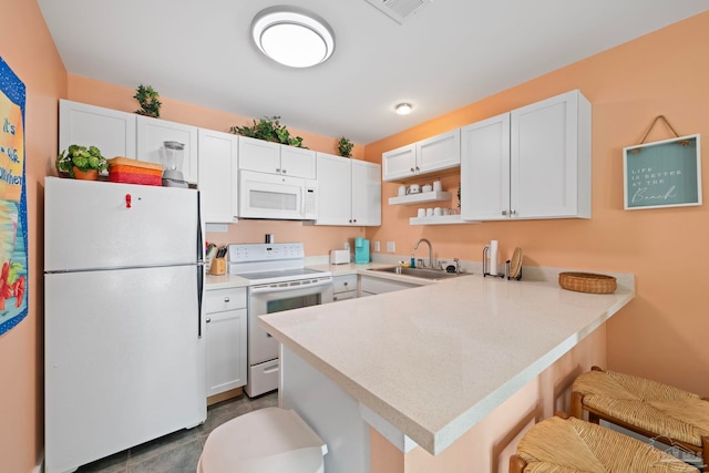 kitchen with sink, a breakfast bar area, white cabinets, kitchen peninsula, and white appliances