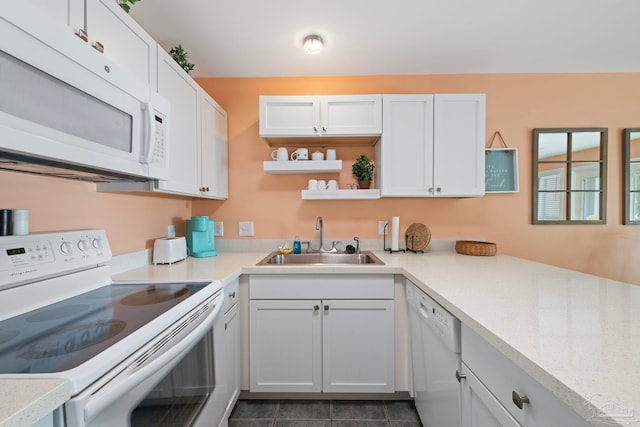 kitchen featuring sink, white cabinets, dark tile patterned floors, light stone countertops, and white appliances