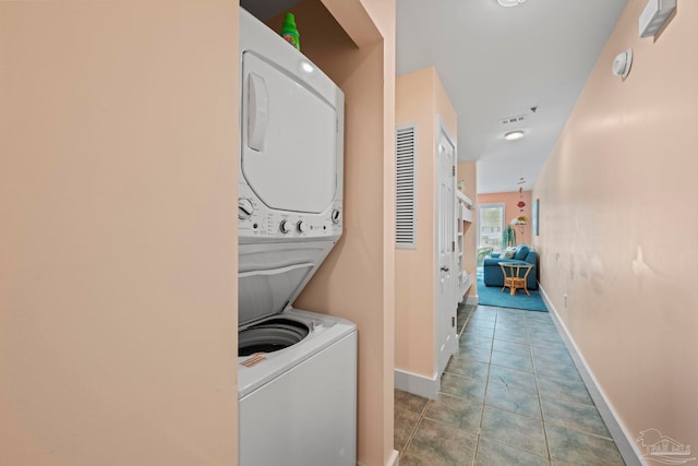 washroom featuring light tile patterned flooring and stacked washer / drying machine