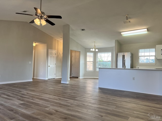 empty room with dark wood-type flooring, ceiling fan with notable chandelier, and vaulted ceiling