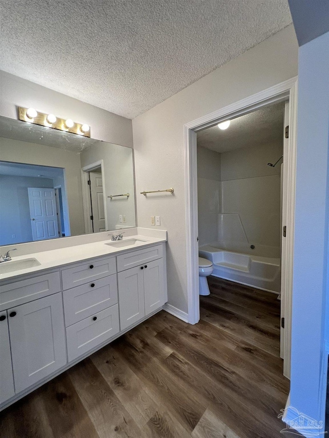 full bathroom with vanity, hardwood / wood-style floors, a textured ceiling, and toilet