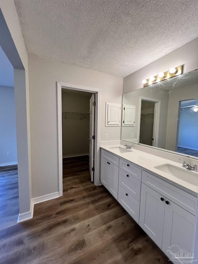 bathroom with wood-type flooring, vanity, and a textured ceiling