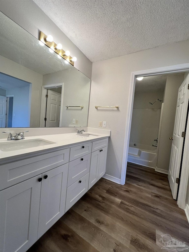 bathroom featuring washtub / shower combination, wood-type flooring, vanity, and a textured ceiling