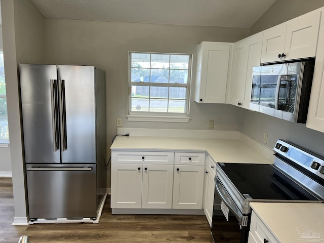 kitchen featuring dark hardwood / wood-style flooring, lofted ceiling, white cabinets, and appliances with stainless steel finishes