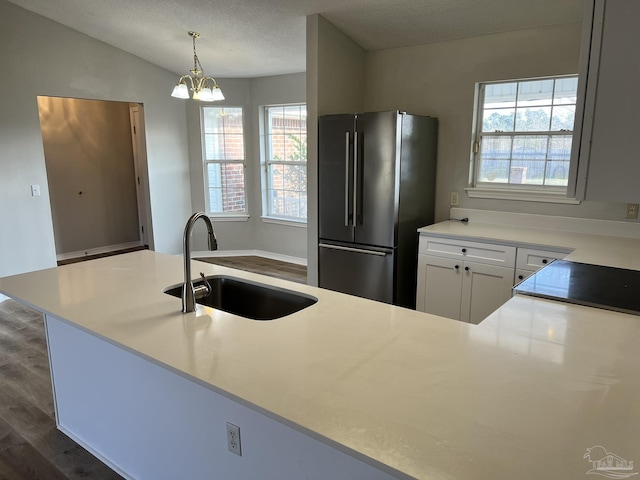 kitchen featuring dark hardwood / wood-style floors, stainless steel refrigerator, decorative light fixtures, sink, and white cabinets