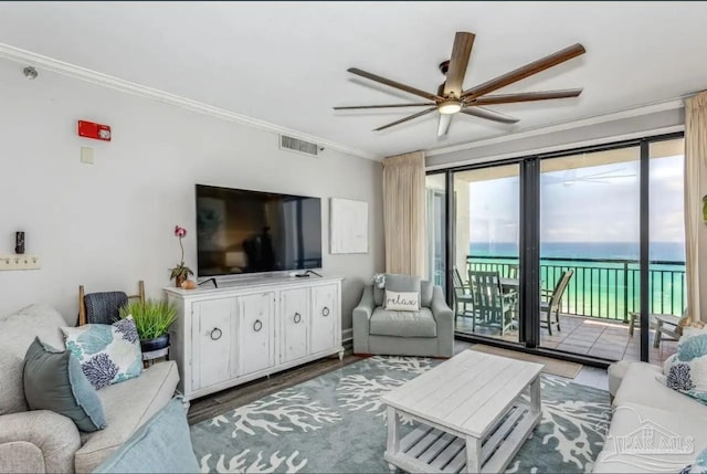 living area with a ceiling fan, visible vents, crown molding, and wood finished floors