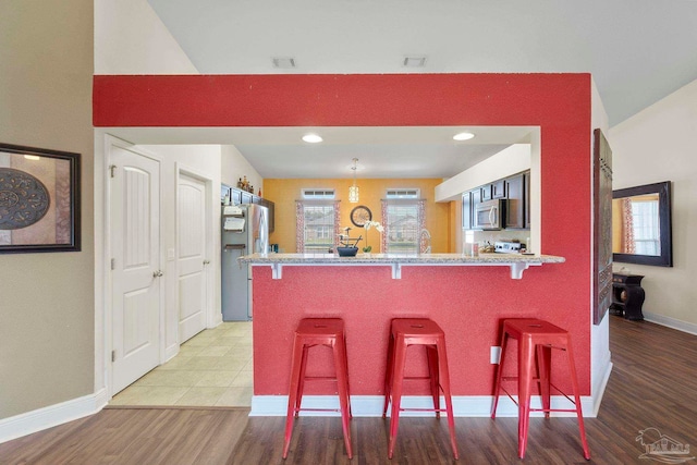 3972 Flour Mill Cir, Pace, FL 32571 - kitchen with stainless steel microwave, freestanding refrigerator, a peninsula, a breakfast bar area, and lofted ceiling