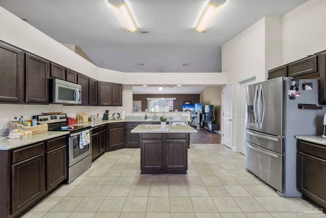 3972 Flour Mill Cir, Pace, FL 32571 - kitchen with stainless steel appliances, vaulted ceiling, dark brown cabinets, light tile patterned floors, and a peninsula