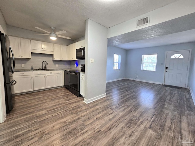 kitchen with white cabinetry, dark wood-type flooring, and black appliances