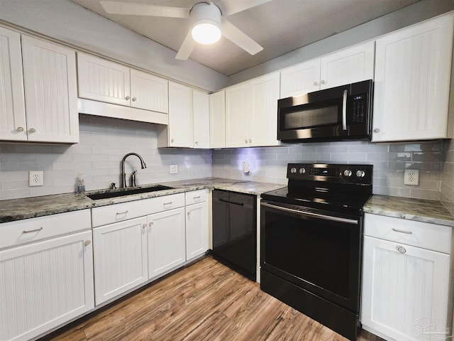 kitchen with backsplash, white cabinetry, sink, and black appliances