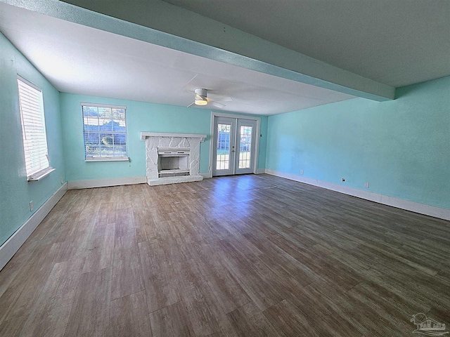 unfurnished living room featuring hardwood / wood-style floors, ceiling fan, beamed ceiling, and french doors