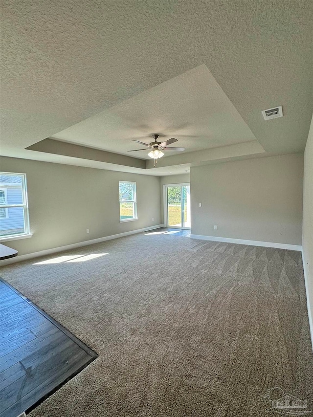 spare room featuring a tray ceiling, carpet floors, a textured ceiling, and ceiling fan