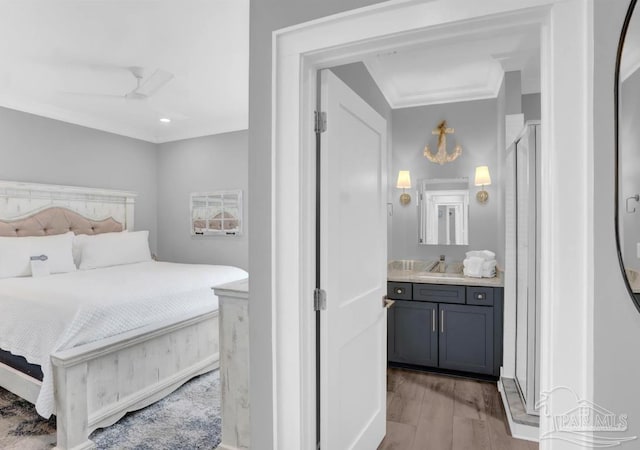 1592 W Beach Blvd Unit Kk, Gulf Shores, AL 36542 - bedroom with light wood-type flooring, crown molding, a sink, and ensuite bath