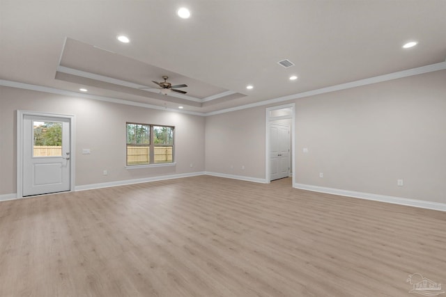 spare room with a tray ceiling, light hardwood / wood-style flooring, and ornamental molding