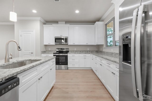 kitchen featuring white cabinetry, sink, stainless steel appliances, light hardwood / wood-style flooring, and ornamental molding