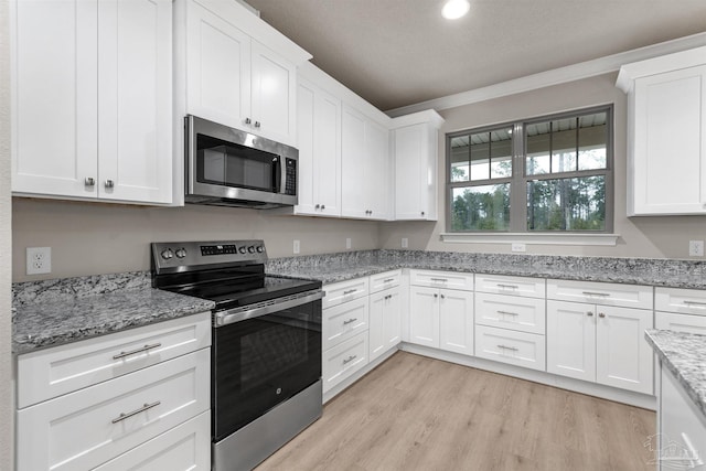 kitchen featuring light stone counters, light hardwood / wood-style flooring, appliances with stainless steel finishes, white cabinets, and ornamental molding