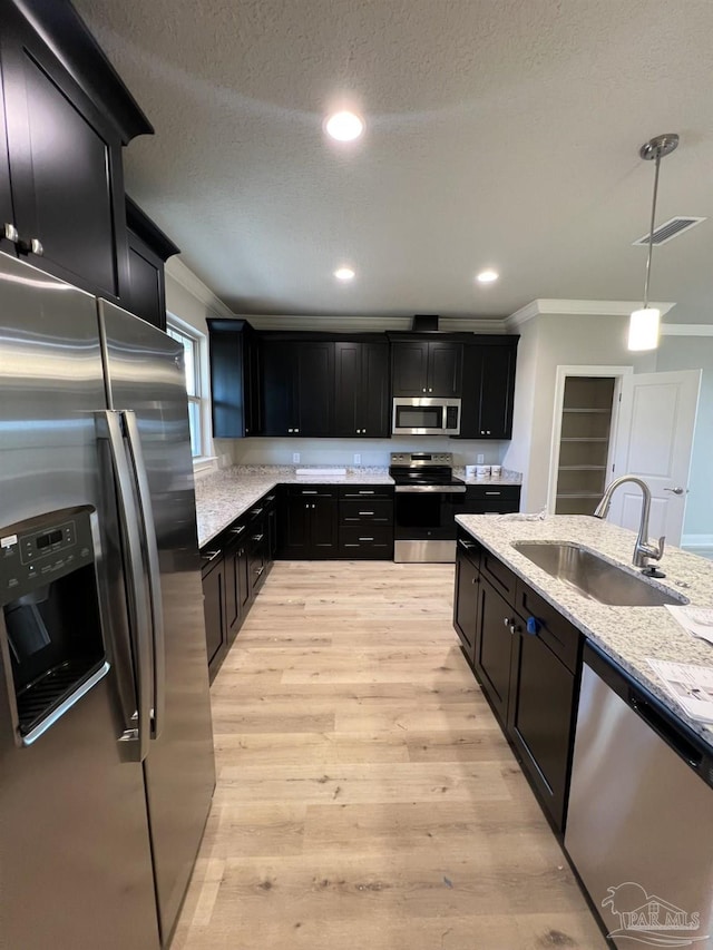 6607 Rocky Shores Rd, Milton, FL 32583 - kitchen with appliances with stainless steel finishes, crown molding, dark cabinetry, light wood finished floors, and light stone counters